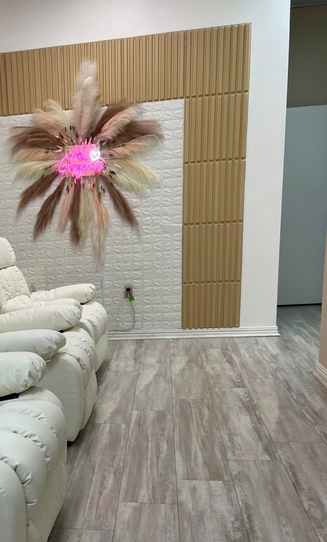 The lounge: a pink neon inside a fan of pampas grass above white recliners